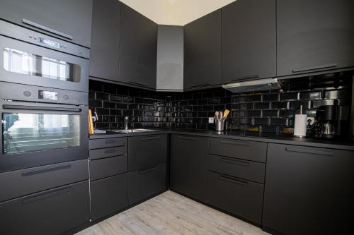 une cuisine avec des armoires noires et des appareils en acier inoxydable dans l'établissement The Loft - Superb 2 bedrooms on top floor with terrace - 10min to Palais & Beach!, à Cannes