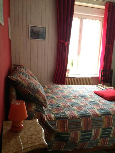 a bedroom with a bed with red curtains and a window at Chez Pierrette in Pont-Croix