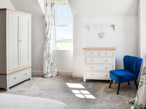 a bedroom with a bed and a dresser and a blue chair at Repentance View in Carrutherstown