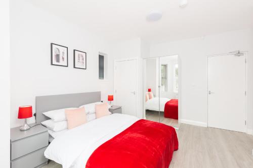 ein weißes Schlafzimmer mit einer roten Decke auf dem Bett in der Unterkunft Hagley Road Apartments - Self Contained Entire Apartments with Kitchen & Netflix - Birmingham City Centre in Birmingham