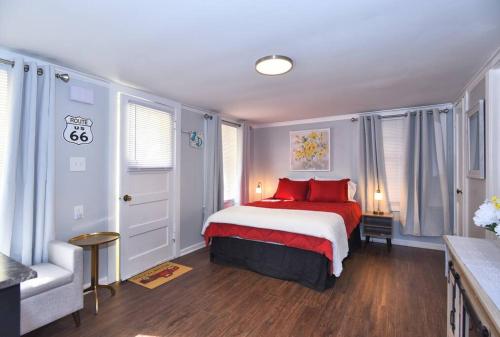 Un dormitorio con una cama con almohadas rojas y una silla en BLUE FLAMINGO'S ADORABLE GUEST HOUSE -TU-Cherry St-Expo-Downtown-11t en Tulsa