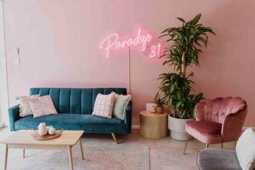 a living room with a blue couch and a neon sign at Paradise 31 - Pink oasis in the heart of the GC in Gold Coast