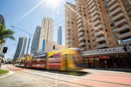 a train traveling down a city street with tall buildings at Paradise 31 - Pink oasis in the heart of the GC in Gold Coast