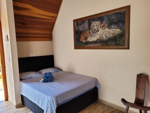 a bedroom with a bed with a picture of a tiger at Chale Vale Encantado in São Bento do Sapucaí