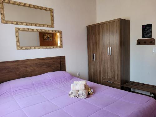 a bedroom with a purple bed with two towels on it at Chale Vale Encantado in São Bento do Sapucaí