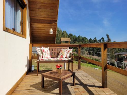a patio with a bench and a table on a deck at Chale Vale Encantado in São Bento do Sapucaí