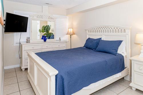 a white bedroom with a bed and a tv at Seaview Duplex 7 in Kure Beach