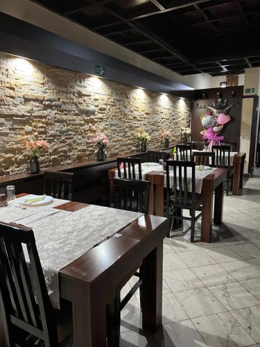 a restaurant with tables and chairs and a stone wall at Garni Hotel City in Kru&scaron;evac