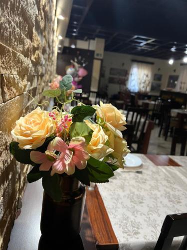 a vase filled with yellow and pink flowers on a table at Garni Hotel City in Kruševac
