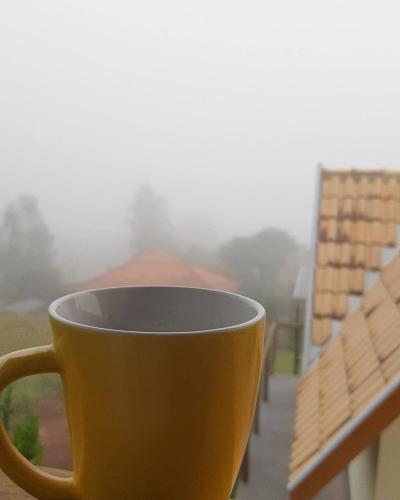 a yellow coffee cup sitting on a window sill at Chale Vale Encantado in São Bento do Sapucaí