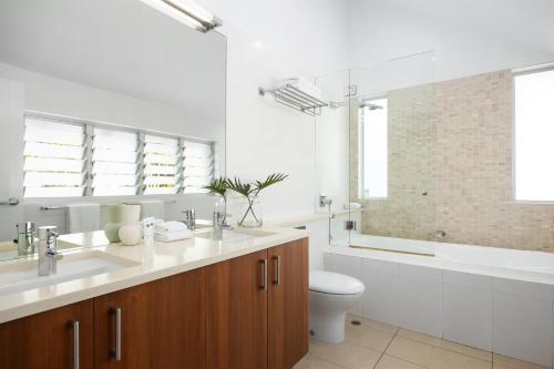 een badkamer met een wastafel, een toilet en een bad bij Villa Bianco, 5 Key Court, Noosa Heads in Noosa Heads