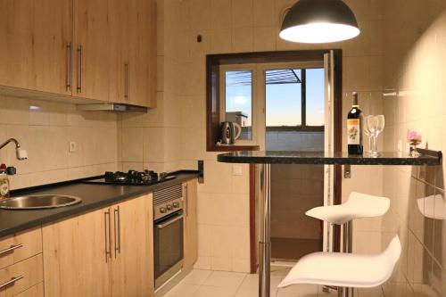 a kitchen with a counter and some white chairs in it at Сomfortable apartments and free garage parking in Porto