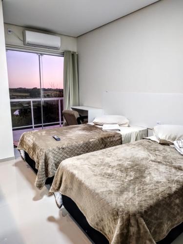 a hotel room with two beds and a window at Hotel Pousada Friedenau in Hulha Negra