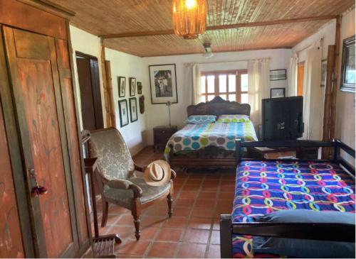 a bedroom with a bed and a chair and a tv at Mirador de los Vientos in Manizales