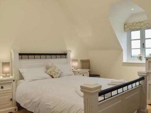 a bedroom with a large bed with white sheets and a window at The New Inn Barn-uk31813 in Marnhull