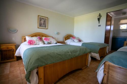 1 dormitorio con 2 camas con sábanas verdes y almohadas rosas en Hotel Jardin del Lago en Las Cabras