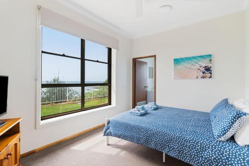 a bedroom with a bed and a large window at Norah Head Seascape in Norah Head