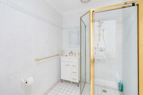 a white bathroom with a shower and a sink at Norah Head Seascape in Norah Head