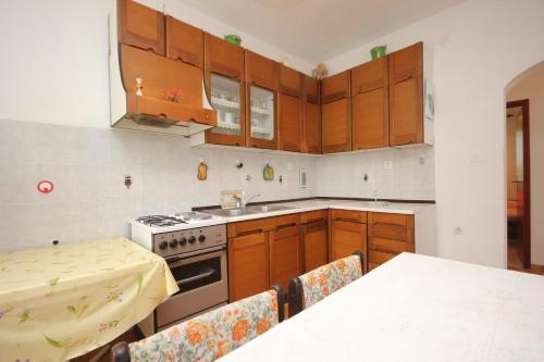 eine Küche mit Holzschränken, einem Herd und einem Tisch in der Unterkunft Apartment Mala Lamjana 827b in Kali