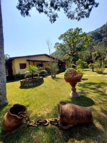 a chain on the grass with a vase and a house at Pousada Fonte Viva - Lumiar in Lumiar