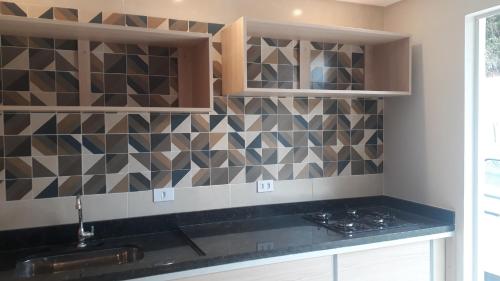 una cocina con encimera negra y azulejos en la pared en Parada Di Maria Guest House en Campos do Jordão