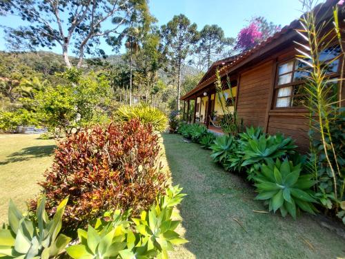 a garden next to a wooden house with plants at Pousada Fonte Viva - Lumiar in Lumiar