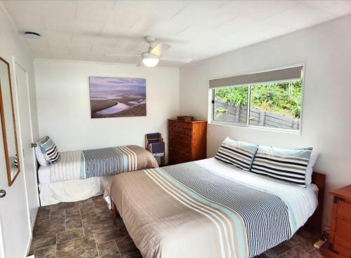 Water's Edge Holiday Home في Opua: غرفة نوم بسريرين ونافذة