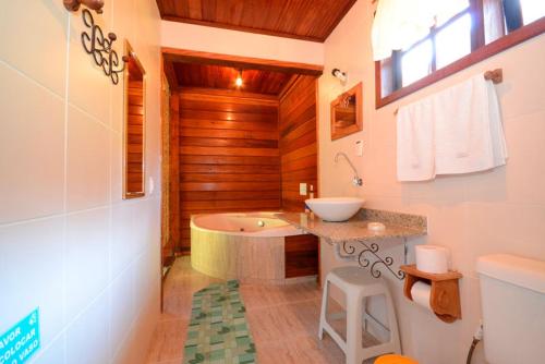 a bathroom with a bath tub and a sink at Pousada Fonte Viva - Lumiar in Lumiar