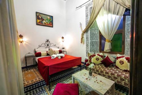 a bedroom with a red bed and a couch at DAR EL AAMOURI in Fès