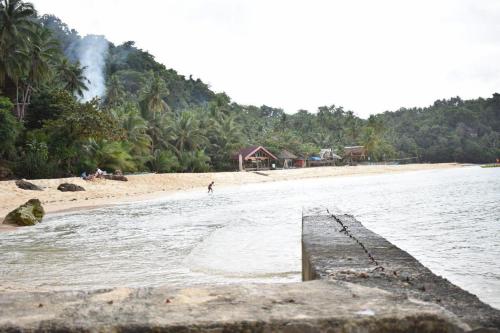 a beach with a person walking in the water at Lorenza's Cottage 1 in Buruanga