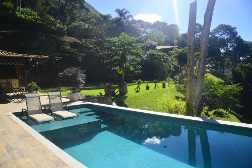 una piscina con 2 sillas y un jardín en Bela vista - Secretário en Petrópolis