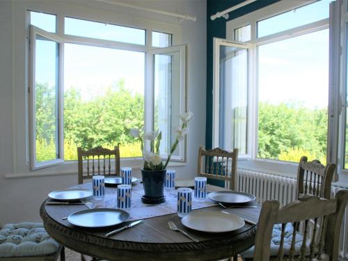 d'une salle à manger avec une table, des chaises et des fenêtres. dans l'établissement Holiday Home near St Jean du Doigt Beach, à Plougasnou