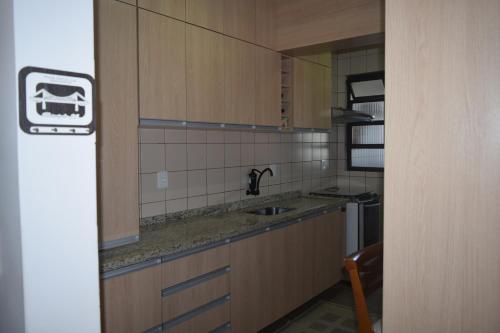 una pequeña cocina con lavabo y espejo en Apartamento Temporada na Praia, en Florianópolis