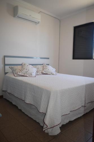 Una cama blanca con sábanas blancas y almohadas. en Apartamento Temporada na Praia, en Florianópolis