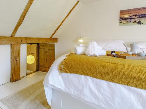 a bedroom with a large bed with white sheets and gold blanket at Angel Lane in Woodbridge