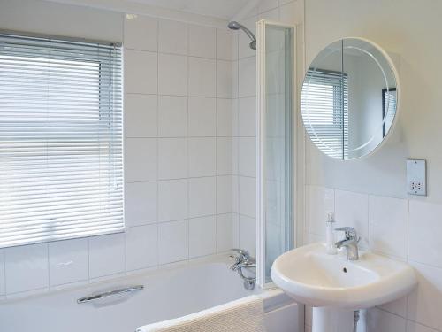 a bathroom with a sink and a tub and a mirror at Whinfell in Newton on the Moor