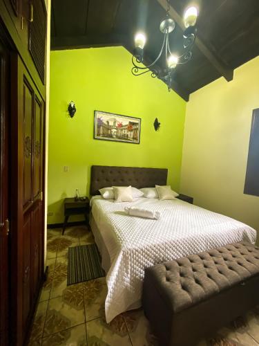 a bedroom with a white bed with a green wall at Real Marquez Hotel in Antigua Guatemala