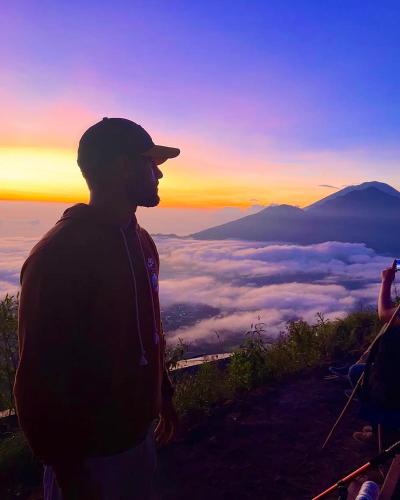 a man standing on top of a mountain looking at the sunset at Batur Homestay and Lodge in Bangli