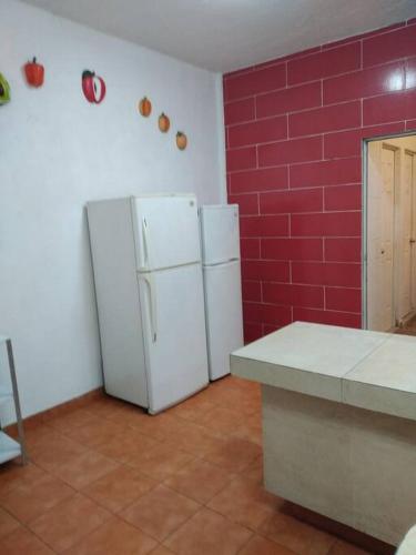 a kitchen with a white refrigerator and a red wall at quintaolivos Jardín y Alberca! in Alpuyeca