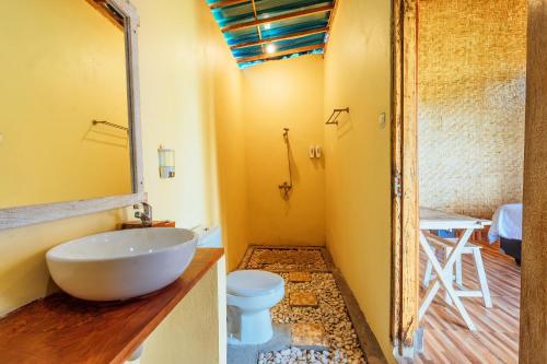 a bathroom with a white sink and a toilet at Atuh Forest Cottage in Nusa Penida