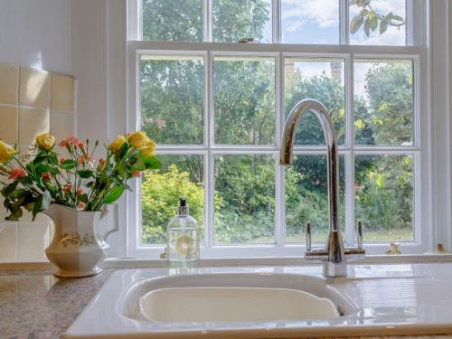 a kitchen sink with a vase of flowers and a window at Middle Cottage in Easton on the Hill
