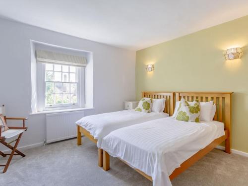 Easton on the Hill的住宿－Middle Cottage，一间卧室设有两张床、一把椅子和一个窗户。