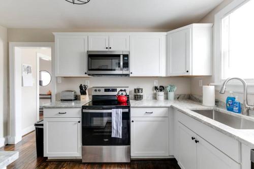 a kitchen with white cabinets and a black stove top oven at Richmond Cottage! 3 BR House in the Heart of RVA in Richmond