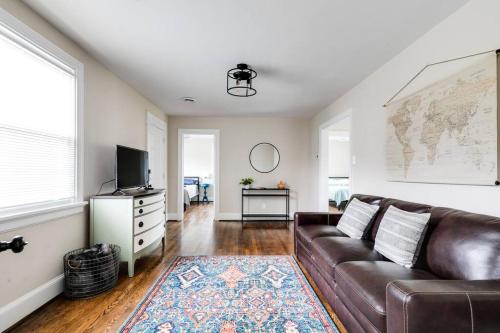 a living room with a brown leather couch and a tv at RVA Cottage Cozy & Spacious Near Downtown in Richmond