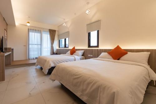 a hotel room with two beds and a television at FUN Style Homestay in Zhuangwei