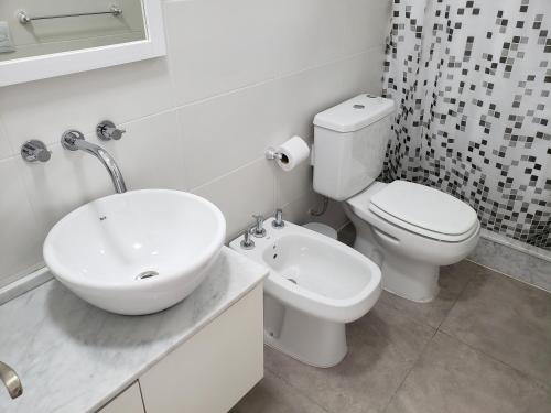 a white bathroom with a sink and a toilet at Departamento Vera Mujica 3 cochera propia incluida in Rosario