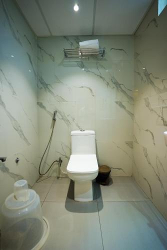 a bathroom with a white toilet in a room at HOTEL SUNRISE HOSPITALITY in Vijayawāda