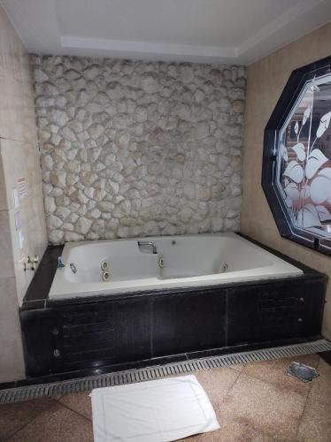 a bath tub in a bathroom with a stone wall at Champion motel in Rio de Janeiro