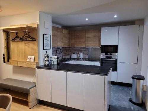 une cuisine avec des armoires blanches et un comptoir noir dans l'établissement Appartement Spa Avec Terrasse, Billard, Babyfoot et Sauna à 500m des Pistes, Parking Inclus - FR-1-275-184, à La Rosière