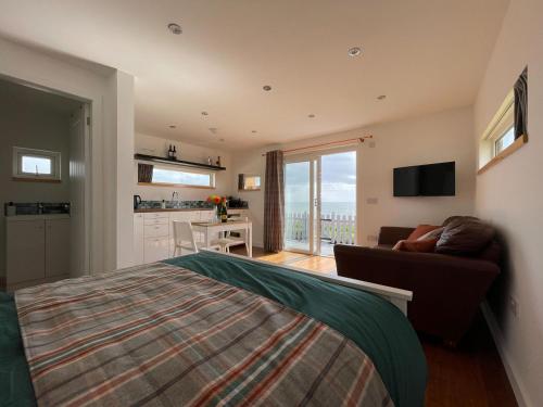 a bedroom with a bed and a couch and a kitchen at Sunrise Summerhouse in Balintore